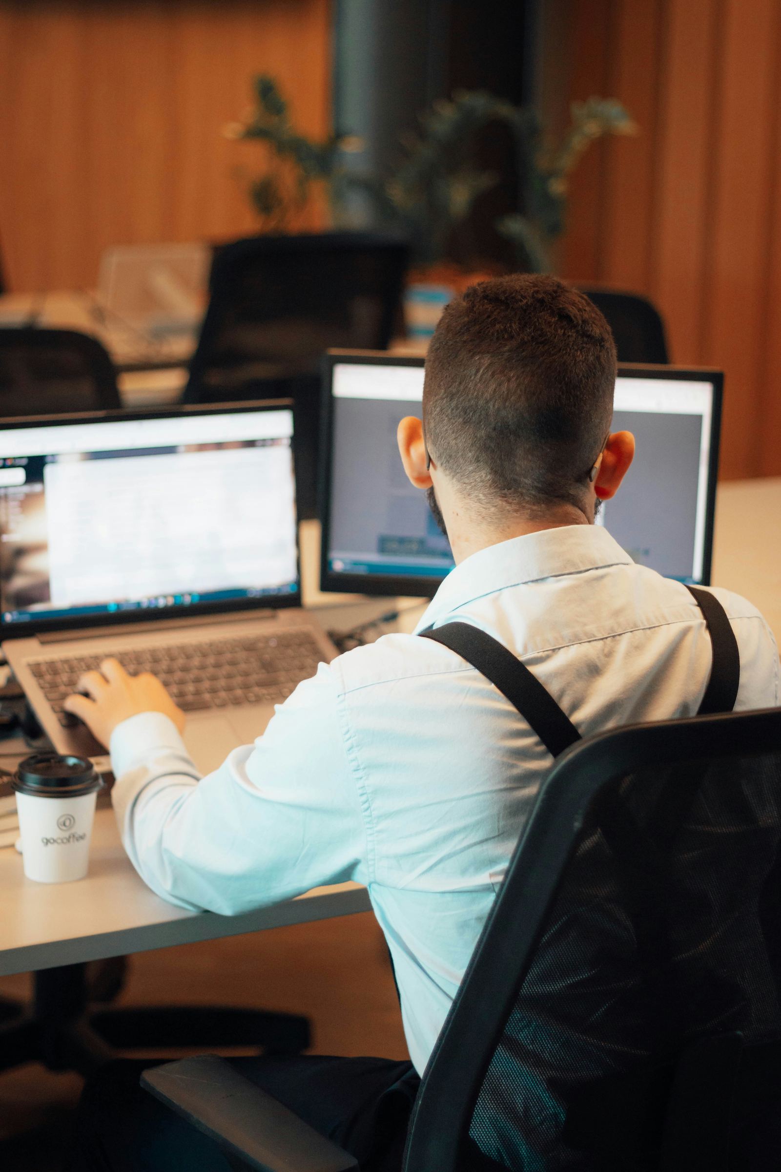 Engineer working across dual monitors and a laptop in an office